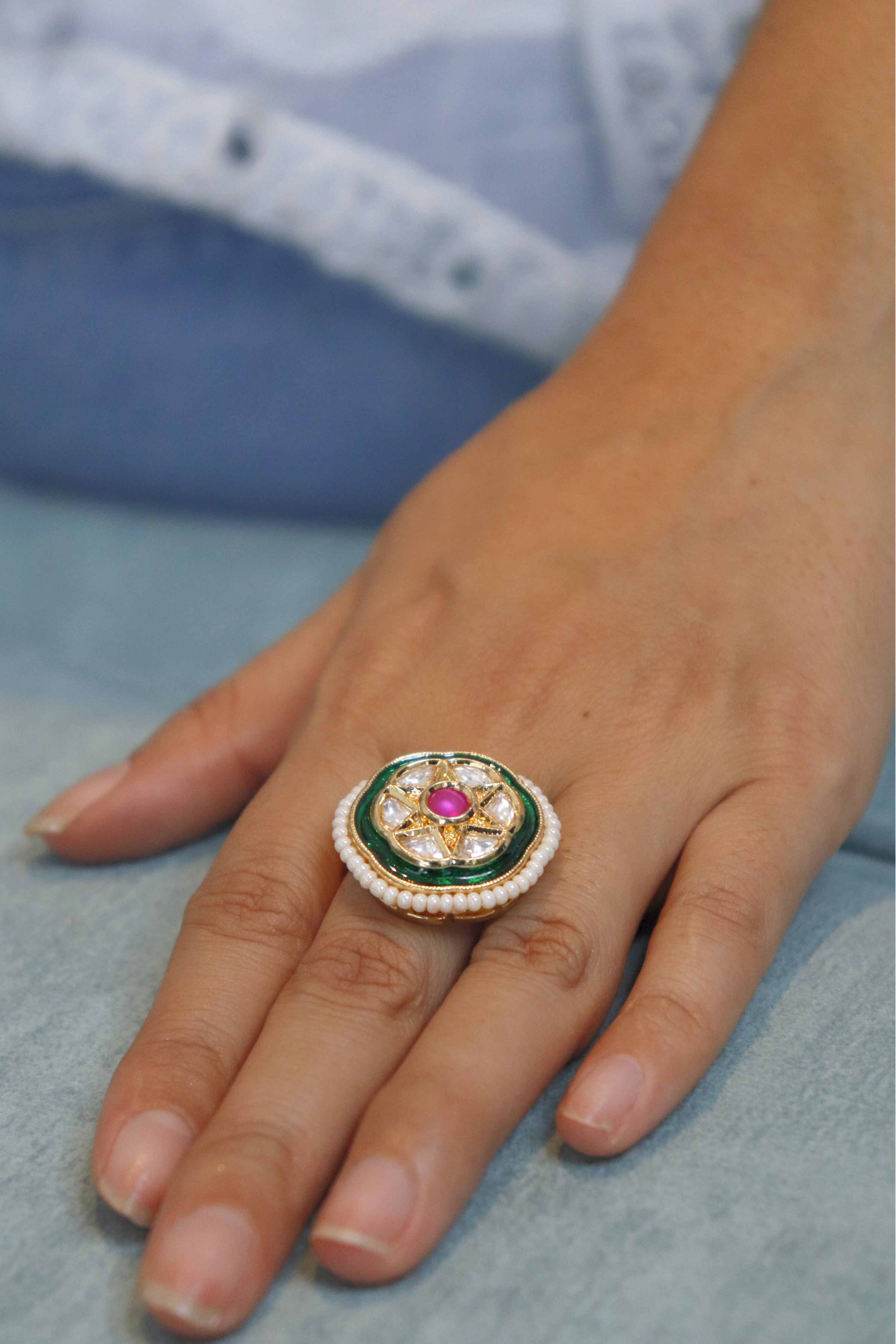 Close-up of a hand wearing an ornate ring with a pink gemstone
