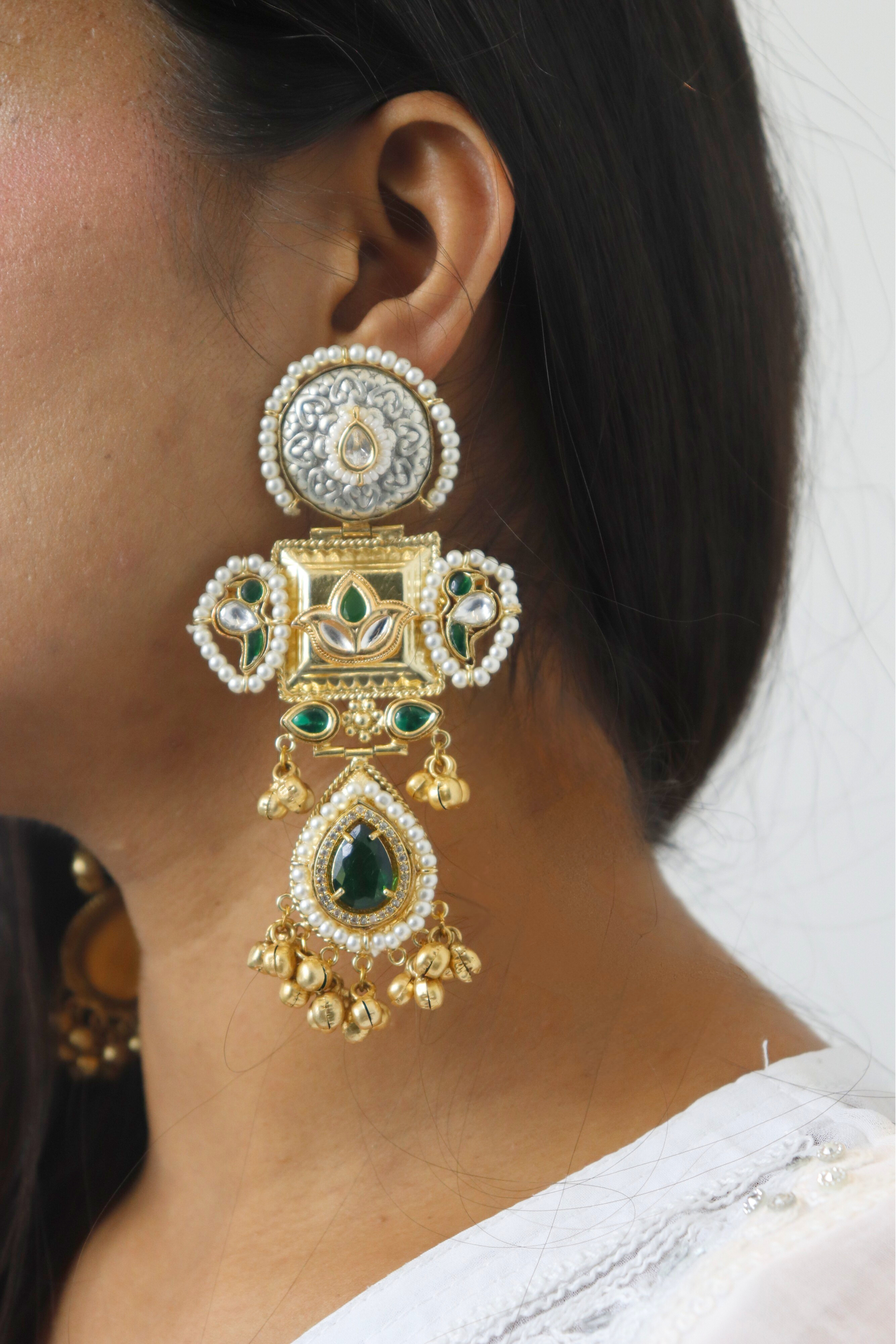 Close-up of a person wearing an ornate gold and green earring.