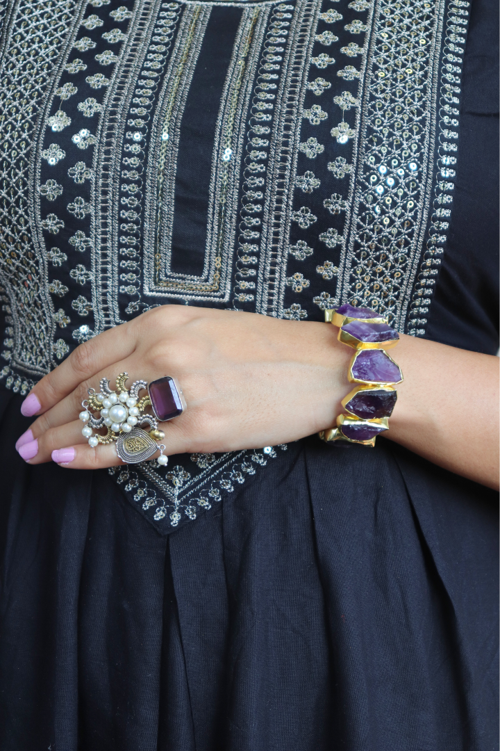 Close-up of a person wearing jewelry with a dark fabric background