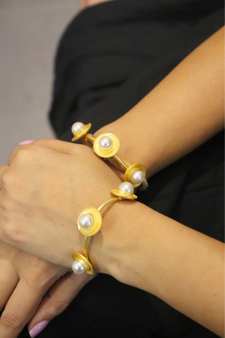 Gold bracelet with pearl accents on a wrist against