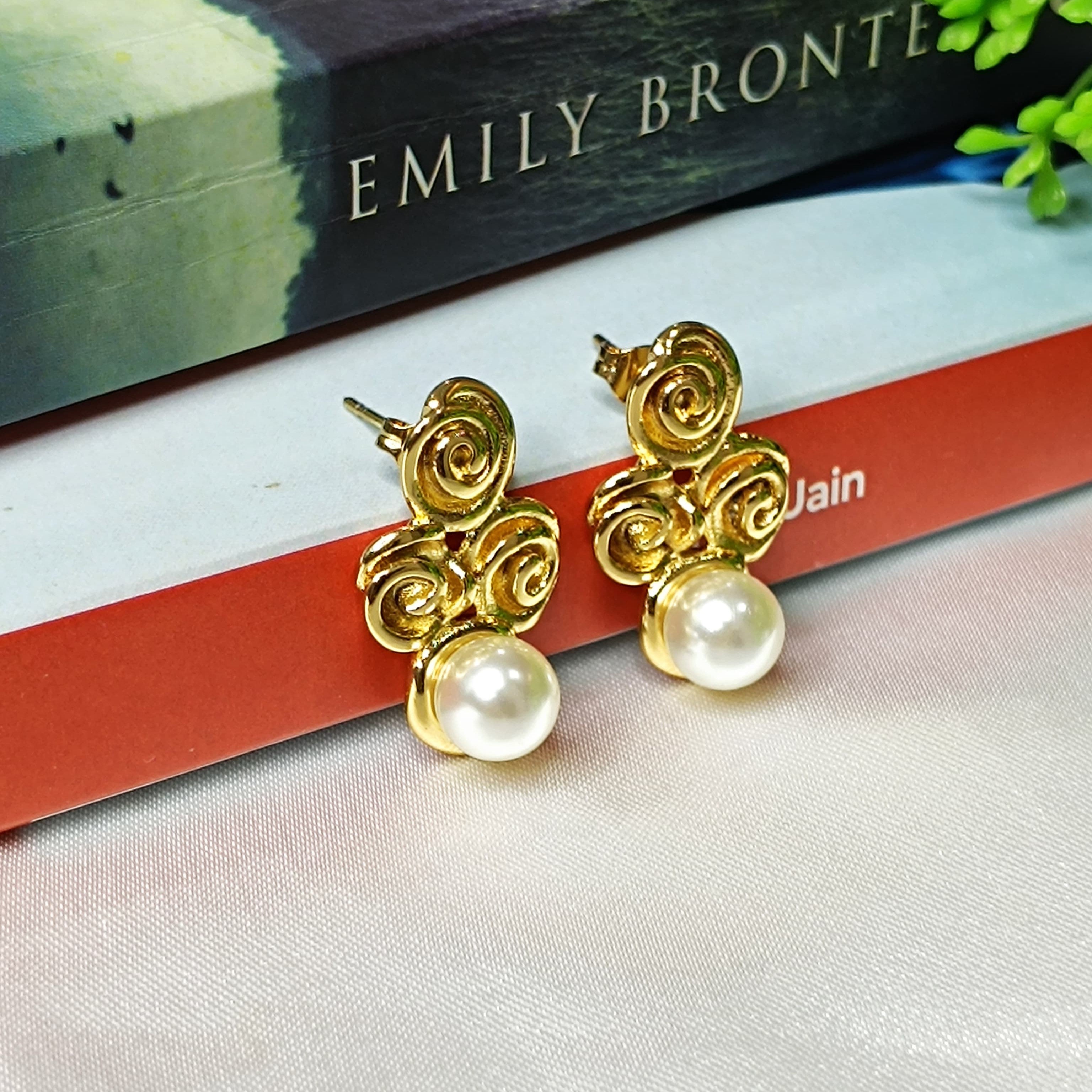 Gold earrings with pearl drops on a book with 'Emily Bronte' visible