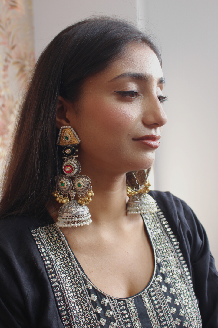 Woman wearing large, ornate earrings with a neutral background