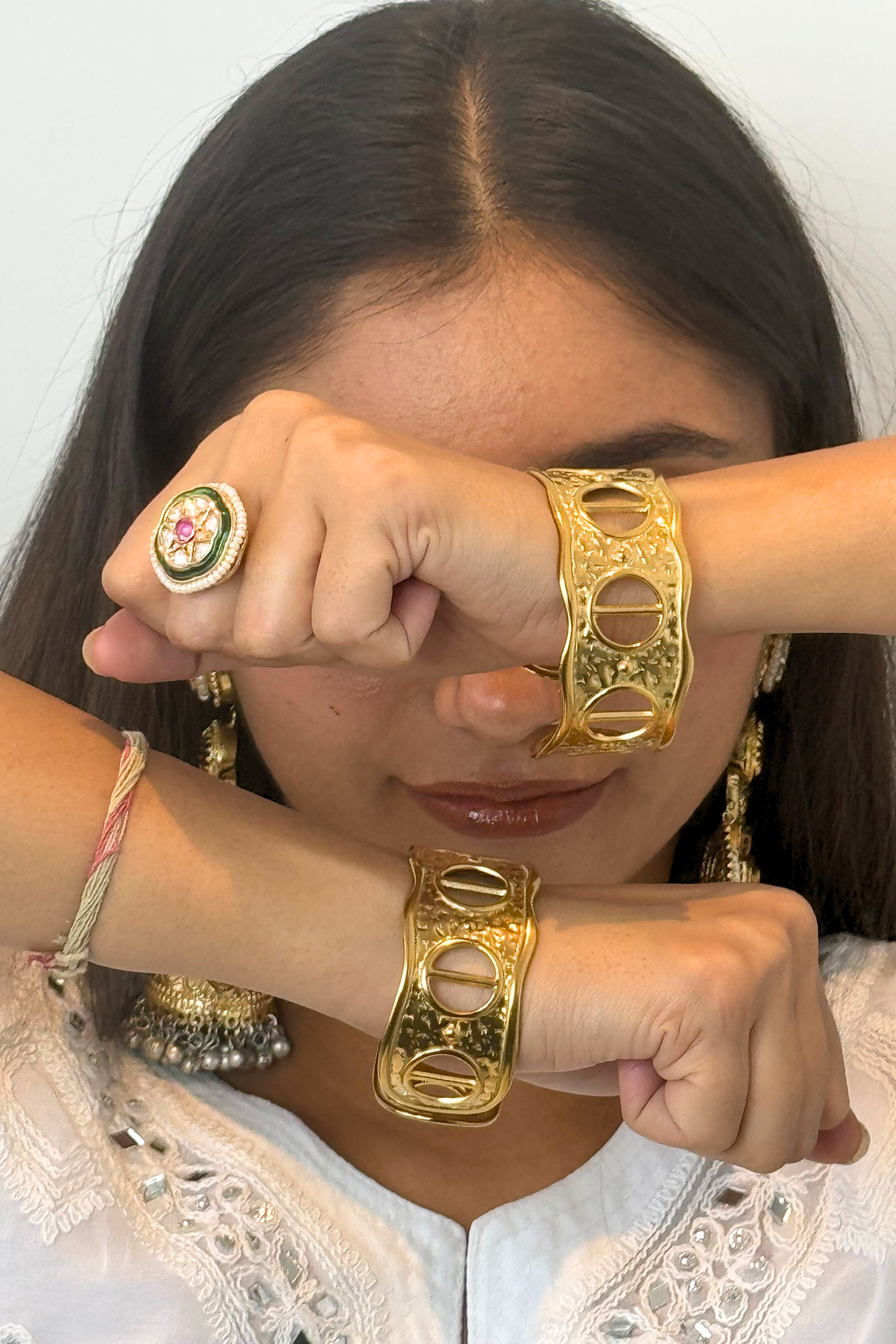 Woman wearing gold jewelry including a ring, bracelet, and earrings