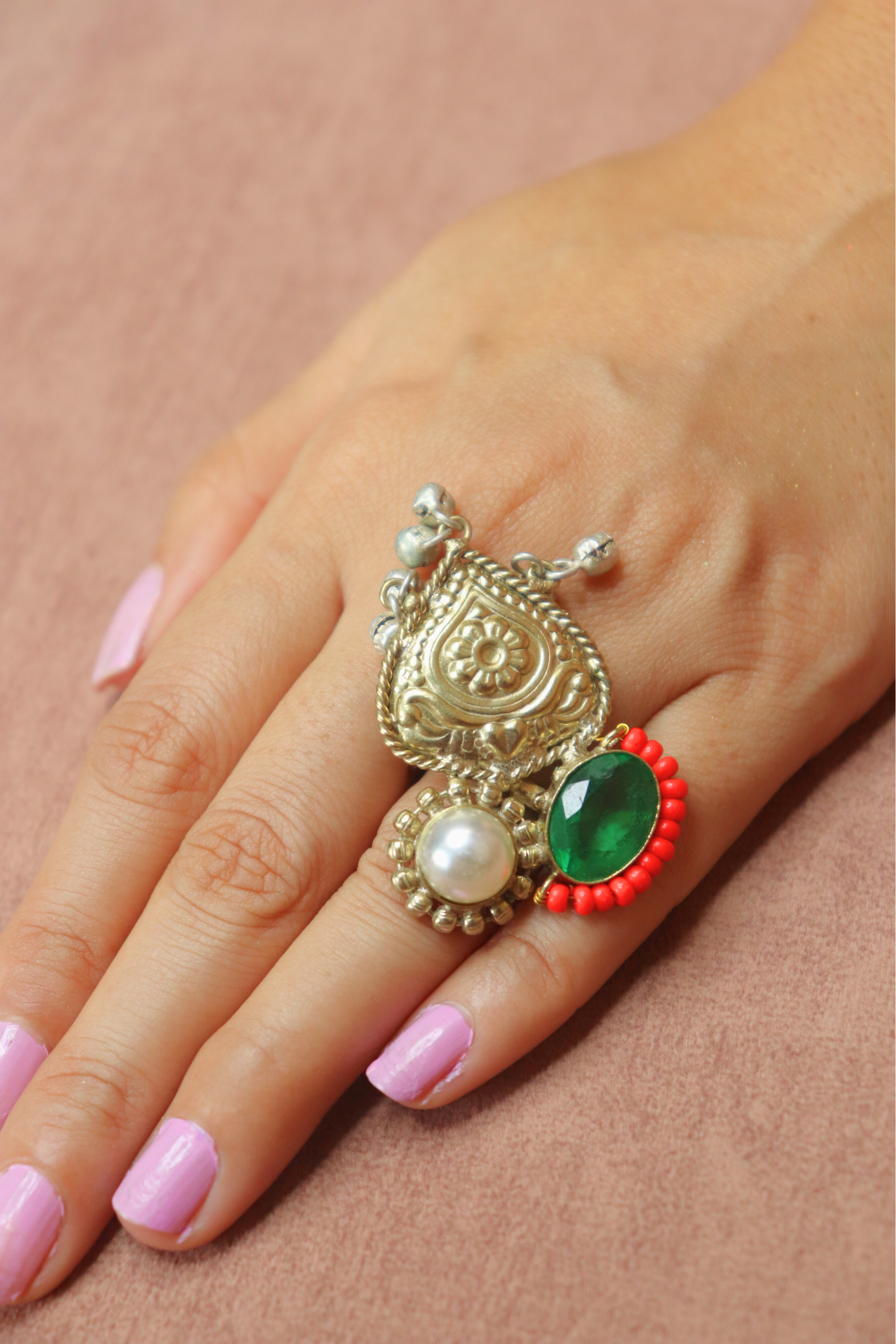 Close-up of a hand wearing an ornate ring with a yellow gemstone and pearl details.