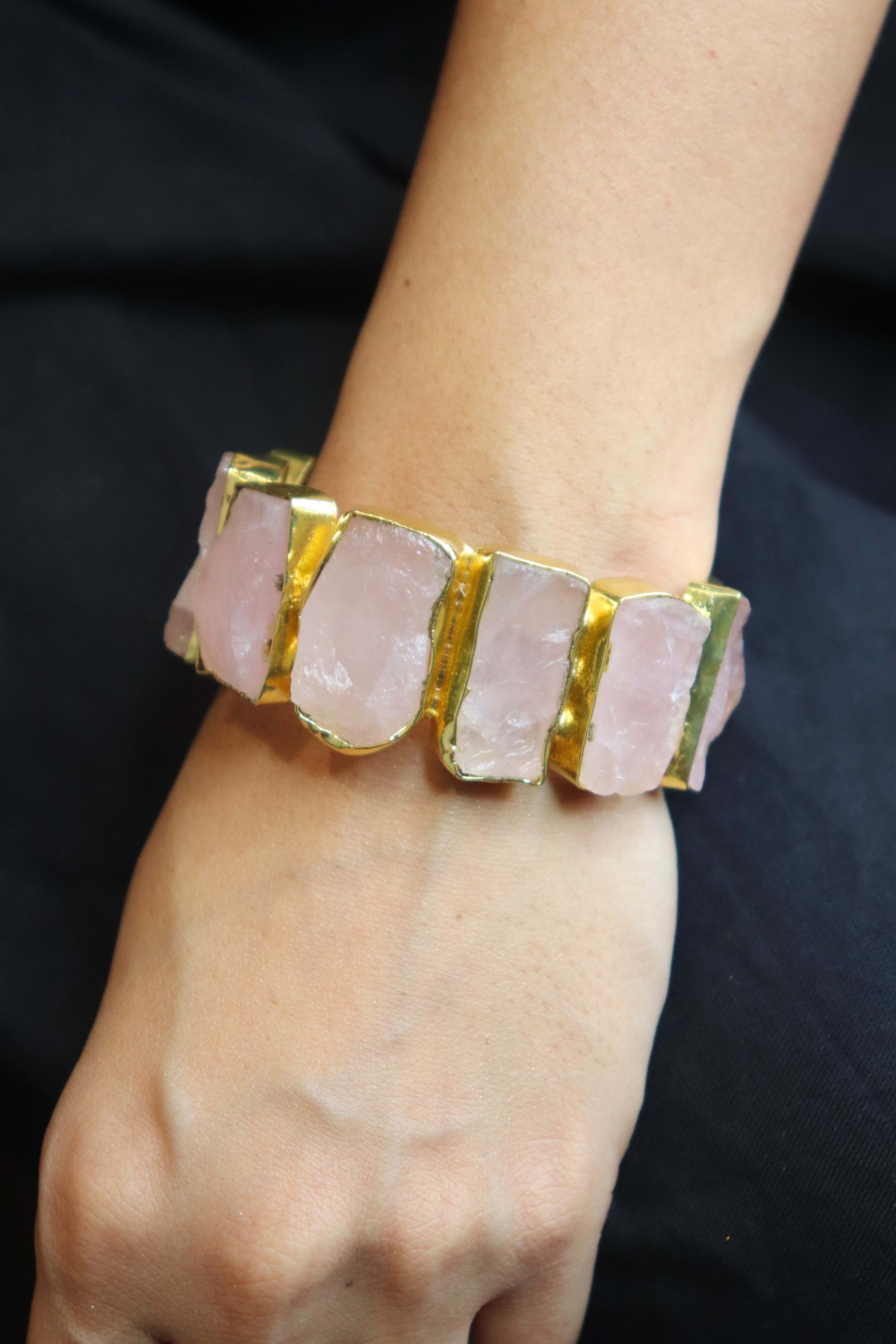 Bracelet with pink stone and gold accents on a wrist against a dark background