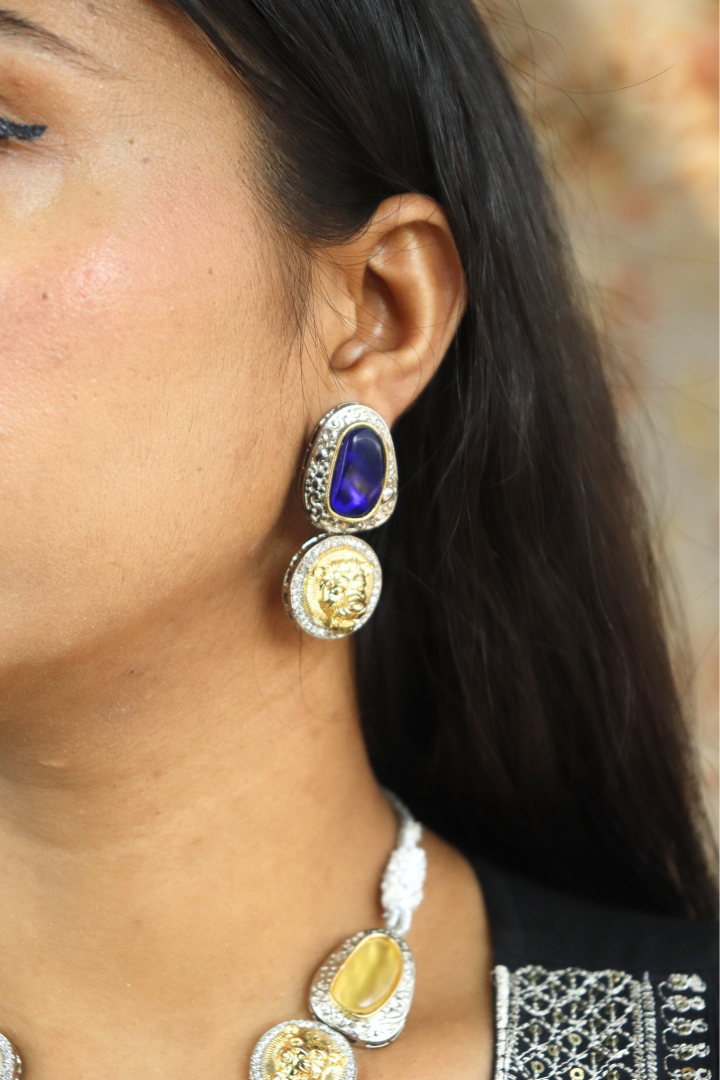 Close-up of a person wearing gold and blue earrings 