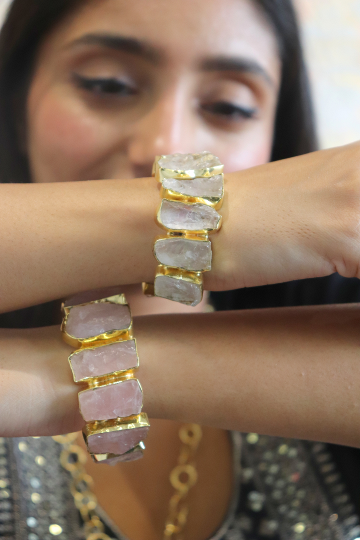 Close-up of a person wearing gold and pink bangles on their wrist.