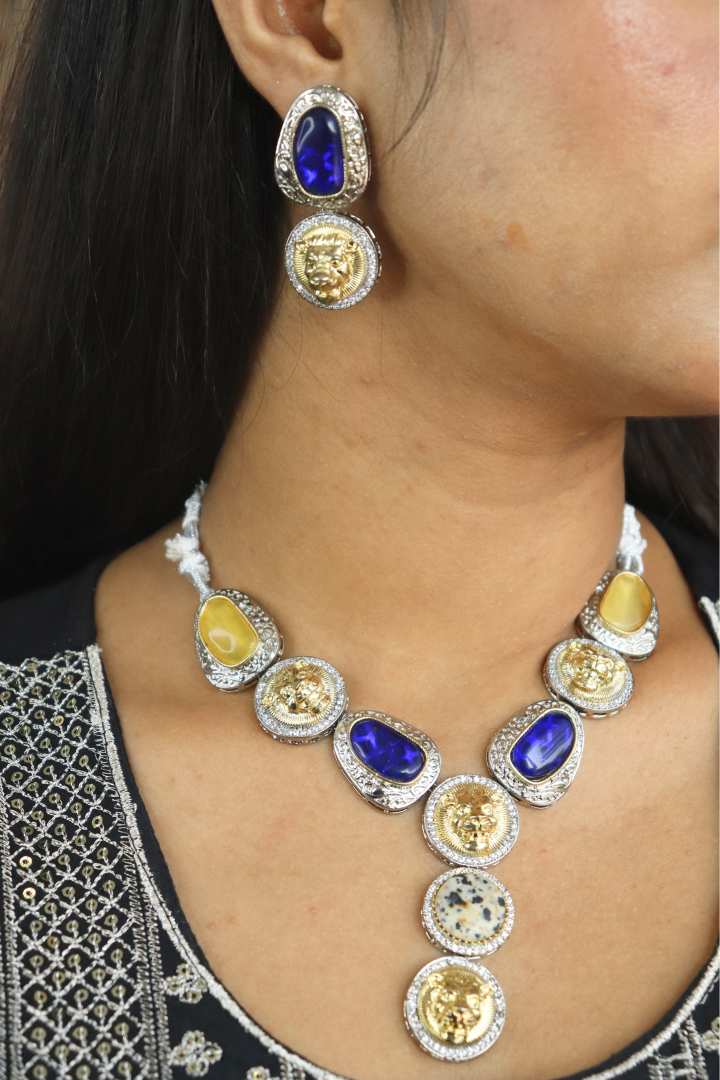 Close-up of a women wearing a necklace and earrings with blue and yellow gemstones.