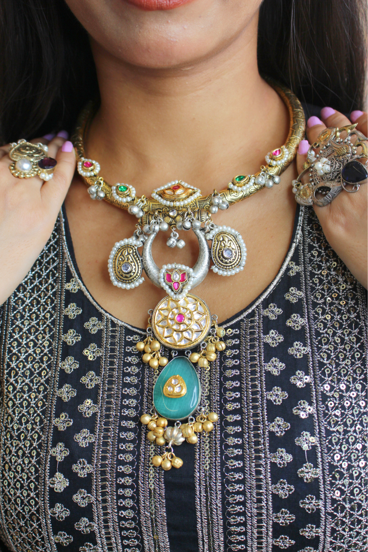 Close-up of a women wearing an ornate necklace with intricate designs and colorful stones.