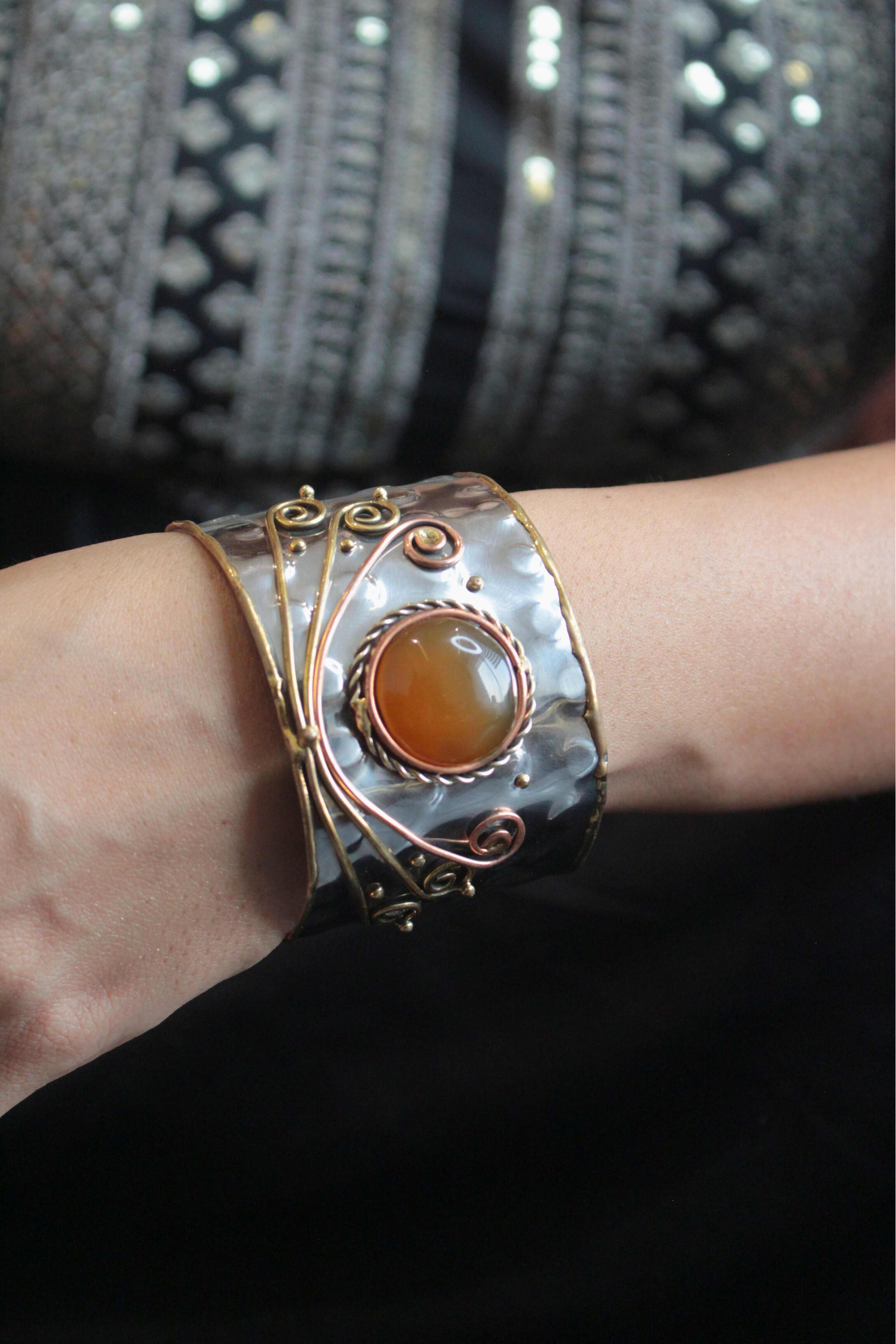 Cuff bracelet with a large amber stone on a wrist 