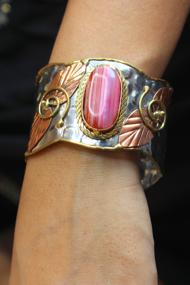 Decorative bracelet with a pink stone on a wrist against 