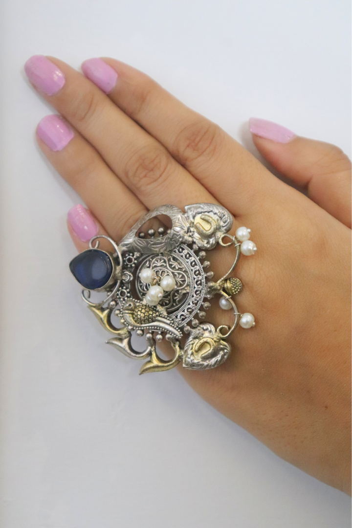 Decorative ring with blue stone and pearl on a hand 
