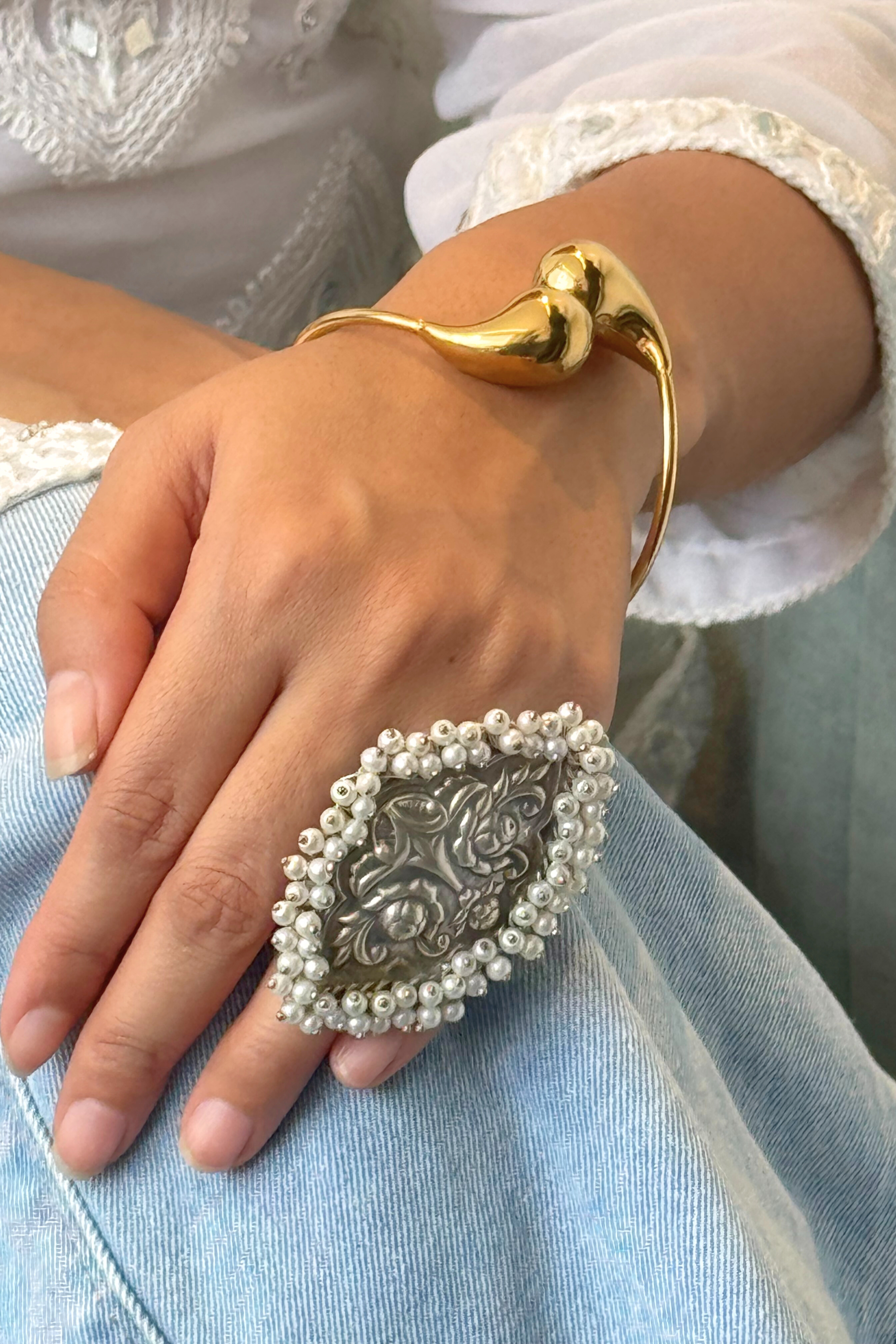 Gold bracelet and silver ring with intricate design on a wrist 