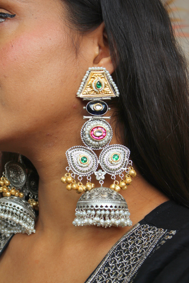 Close-up of a women wearing large, ornate earrings with intricate designs.